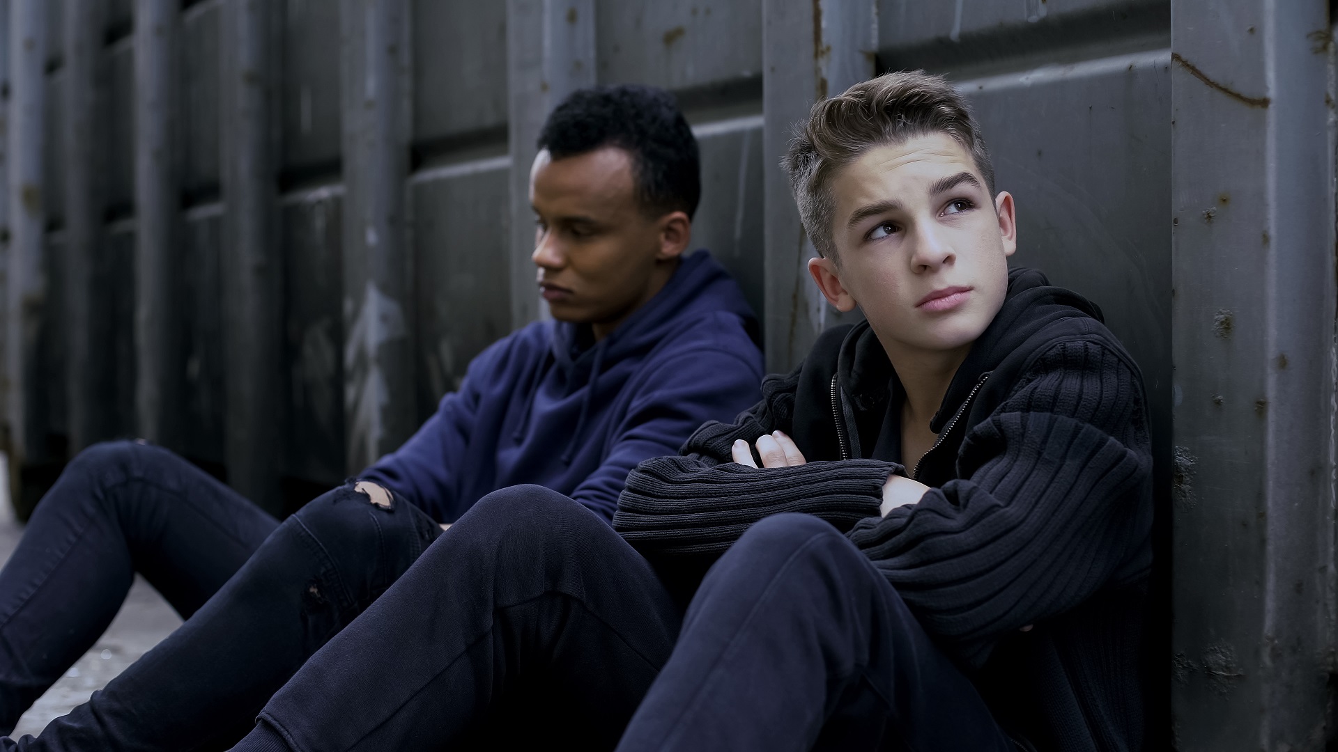 Two teenage boys sitting by a wall